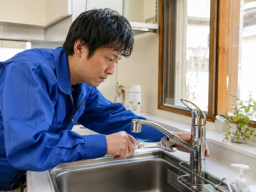 キッチンの混合水栓を工具で修理する作業の様子